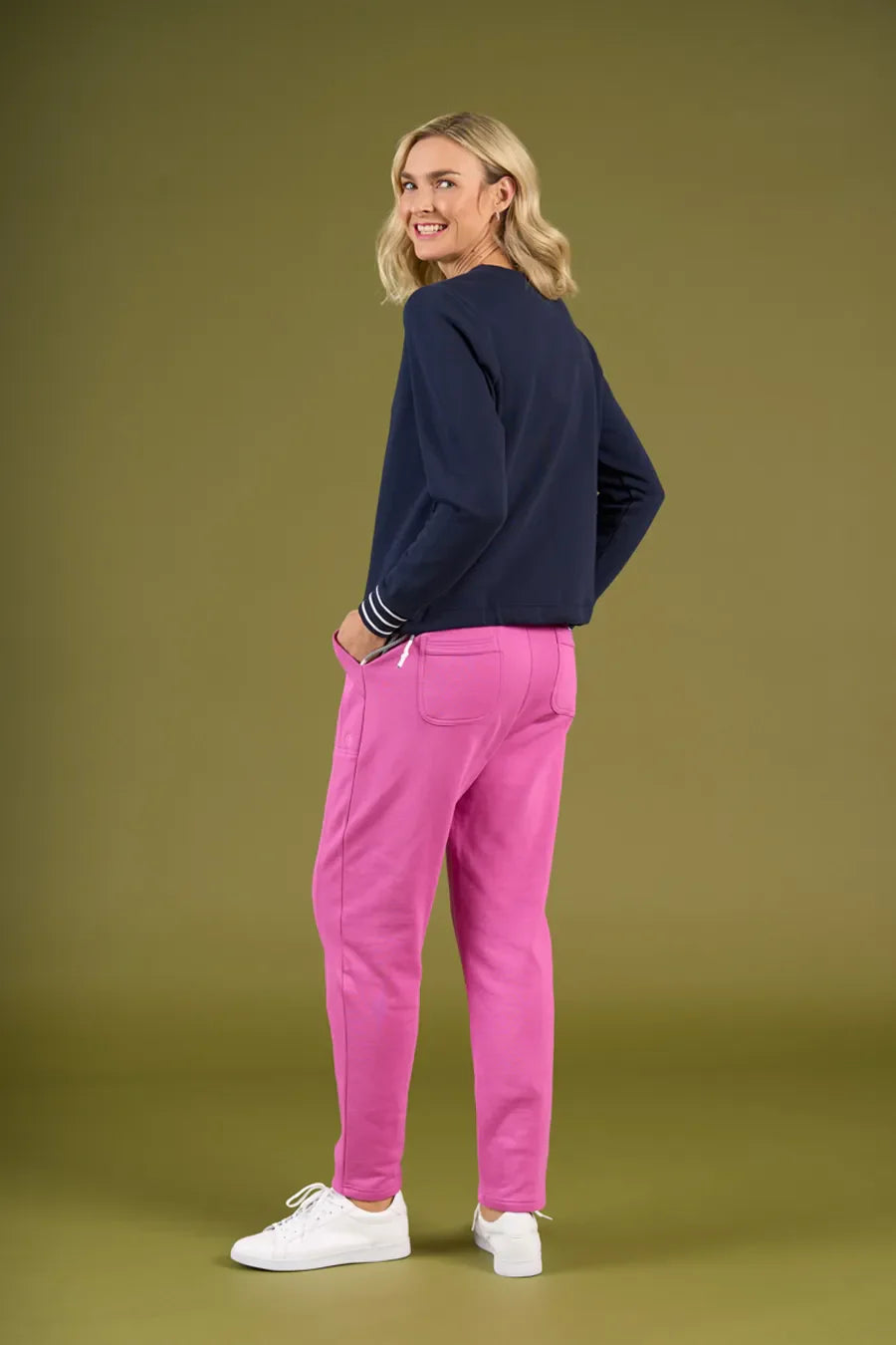 Woman wearing a navy sweater and pink pants on a green background