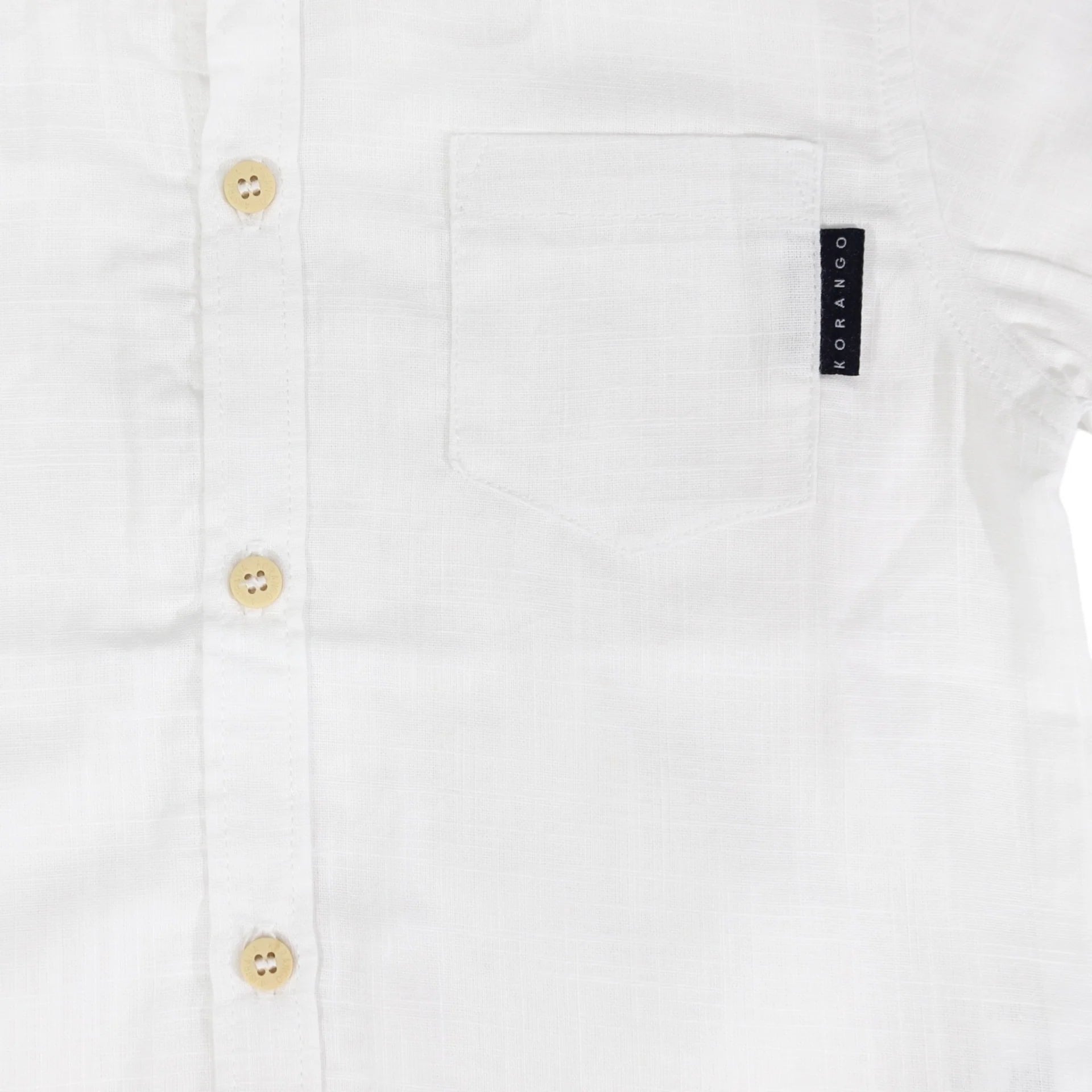 Close-up of a white shirt with button details and a brand label on a white background