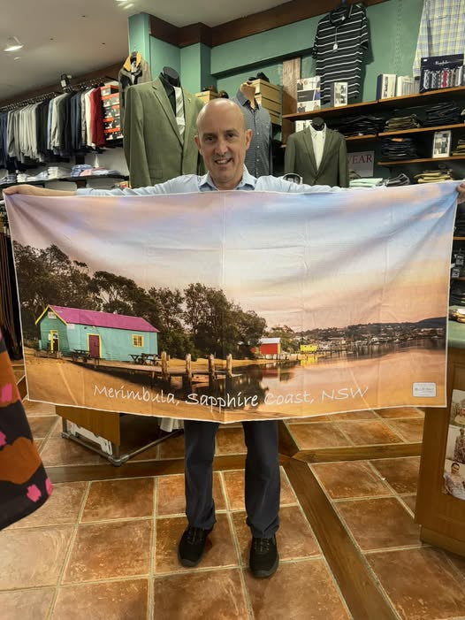 Man holding a large scenic towel in a store