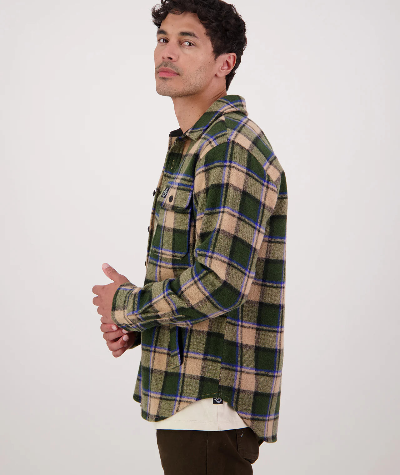 Man wearing a green and beige plaid shirt on a white background