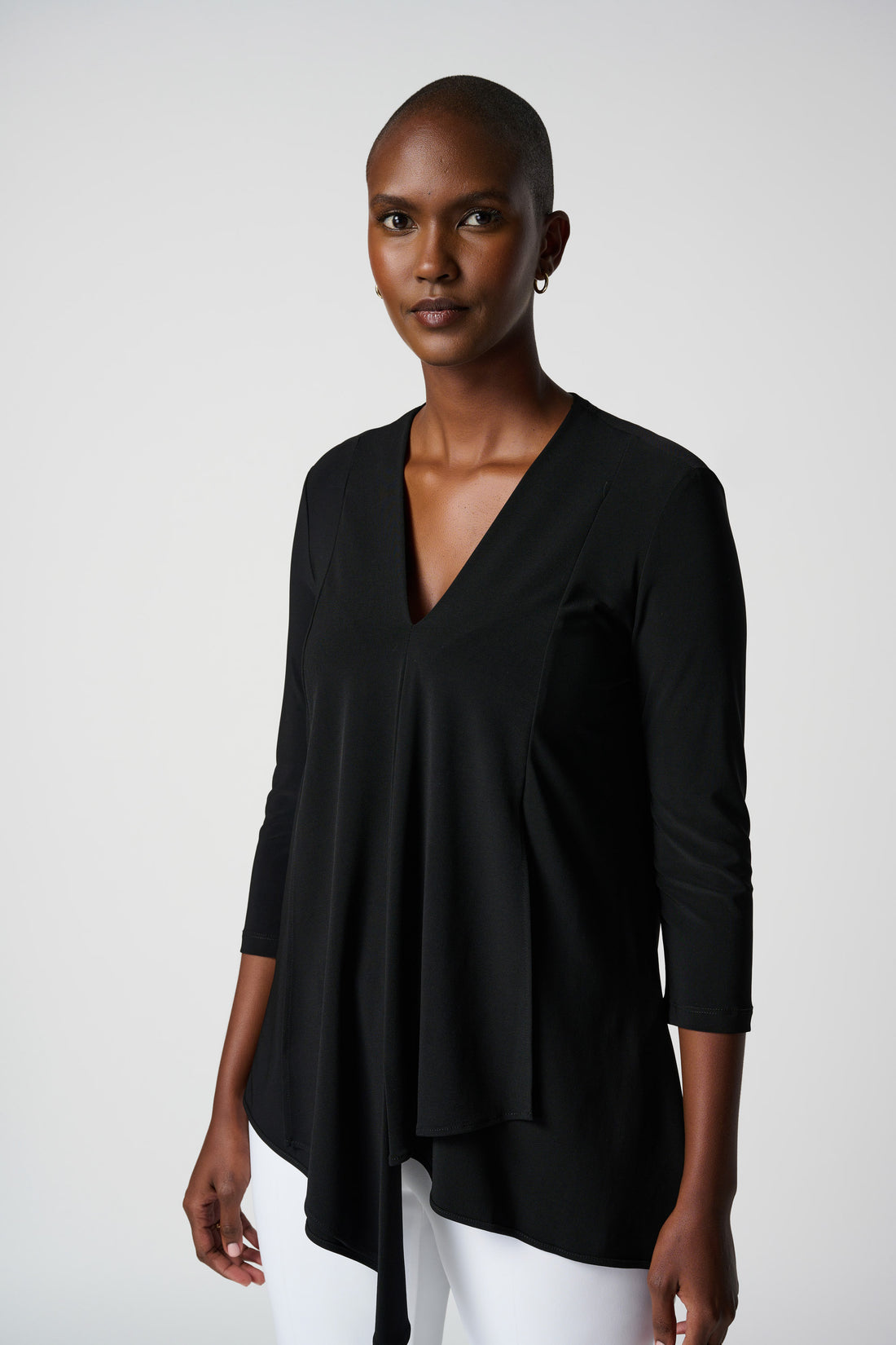 A woman wearing a black asymmetric waterfall tunic with three-quarter sleeves and a V-shape neckline.