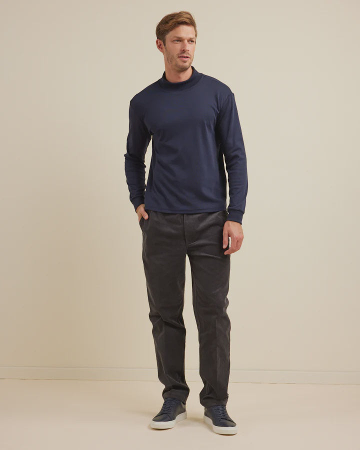 Man wearing a navy long-sleeve shirt and dark pants against a beige background
