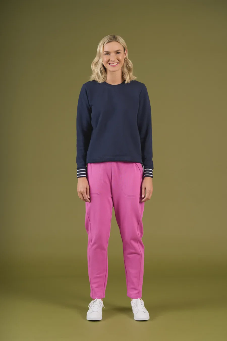 Woman wearing a navy sweater and pink pants on a green background