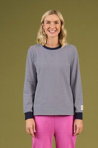 Woman wearing a striped shirt and pink pants against a green background