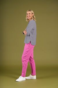 Woman wearing a gray blazer and pink pants on a green background