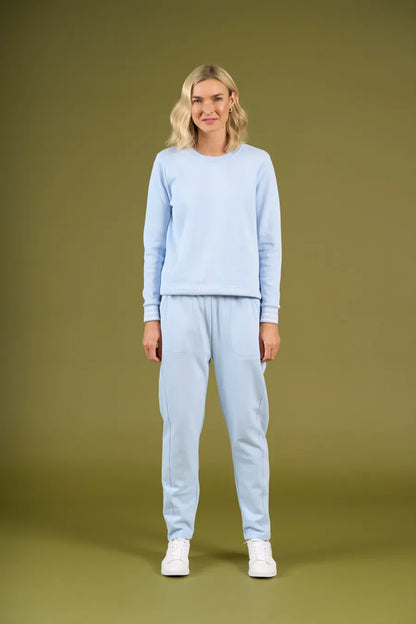 Woman wearing a light blue sweater and pants on an olive green background