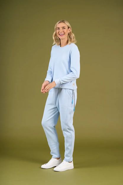 Woman wearing a light blue tracksuit against a green background