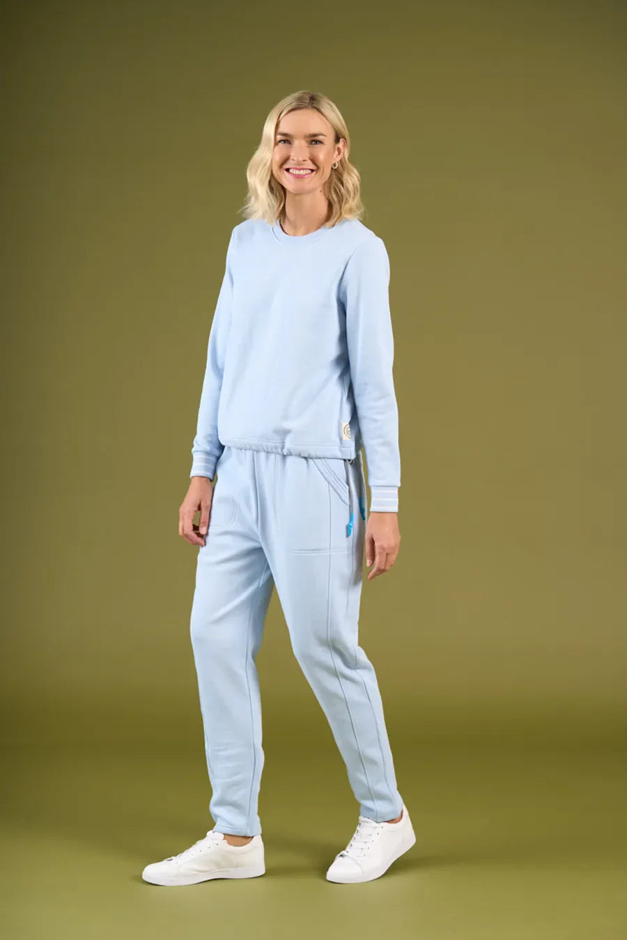 Woman wearing a light blue tracksuit on an olive green background