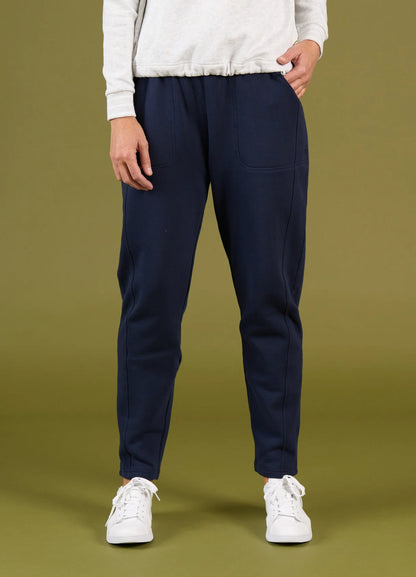 Person wearing navy jogger pants and white sneakers on a green background