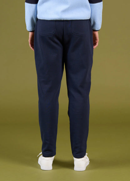 Person wearing navy pants and a light blue sweater on a green background
