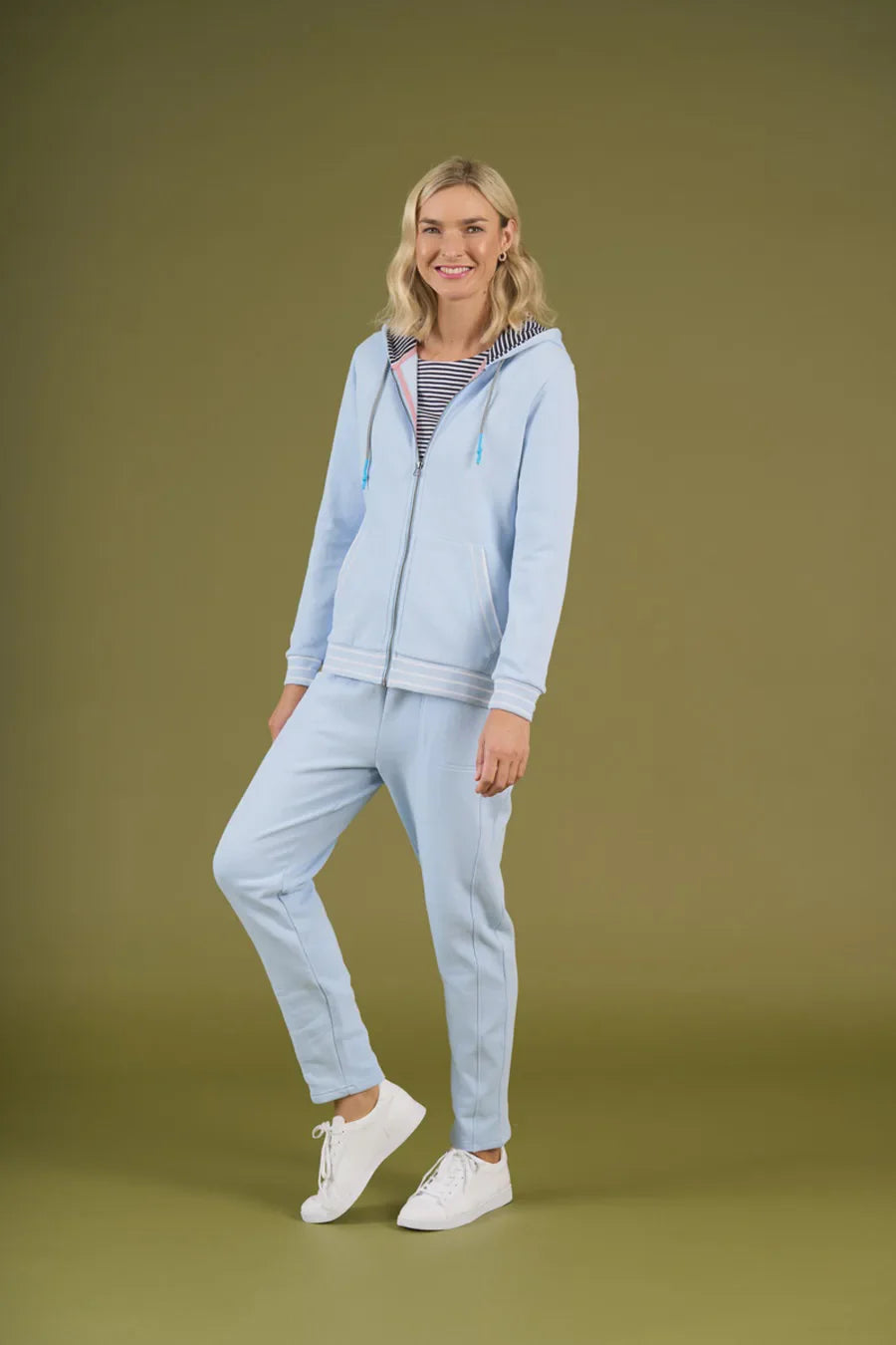 Woman wearing a light blue tracksuit on a green background