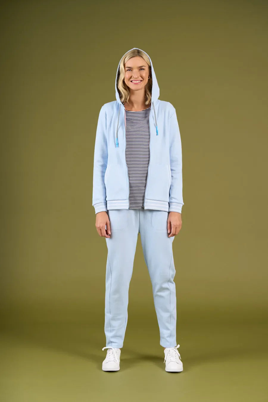 Person wearing a light blue hoodie and pants on a green background