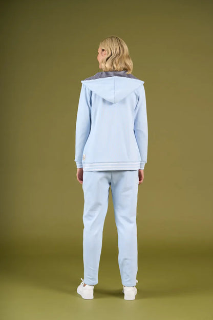 Person wearing a light blue hoodie and pants on a green background