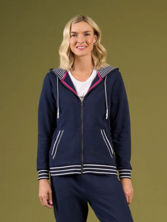 Woman wearing a navy blue tracksuit with pink accents on a green background