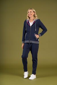 Woman wearing a navy tracksuit with white accents on a green background