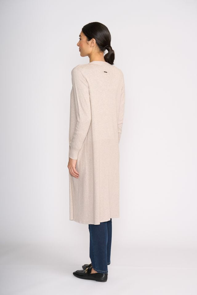 Woman wearing a long beige cardigan over a white shirt with dark pants on a white background