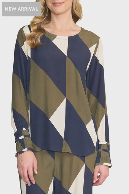 Woman wearing a blue, green, and white patterned top on a white background
