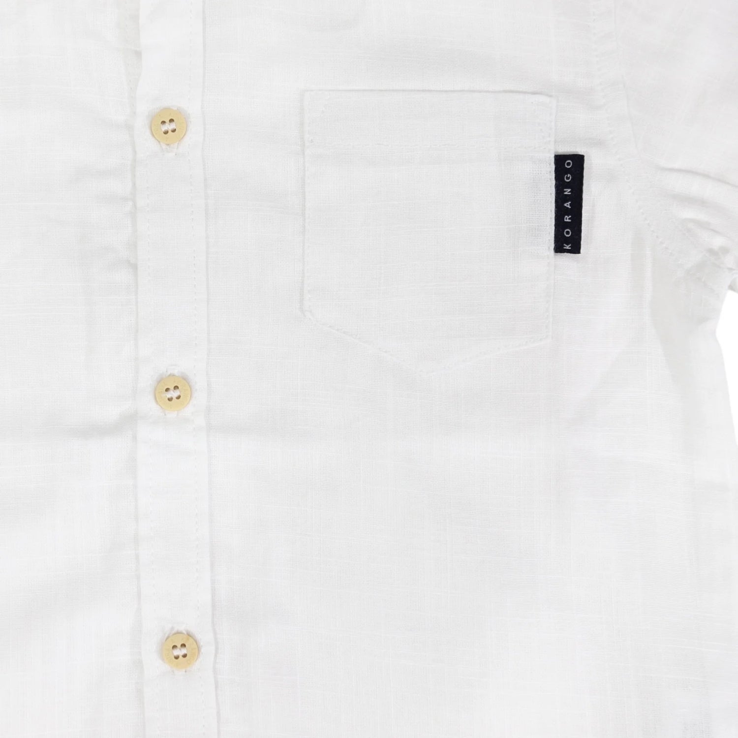 Close-up of a white shirt with button details and a brand label on a white background