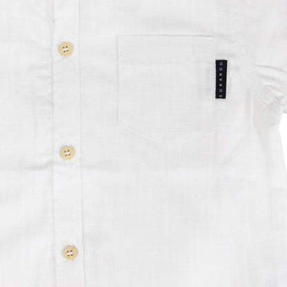 Close-up of a white shirt with button details and a brand label on a white background