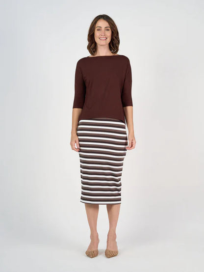 Woman wearing a brown top and striped skirt on a white background
