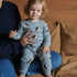 Child wearing a blue pajama set with penguin pattern, sitting on a person&