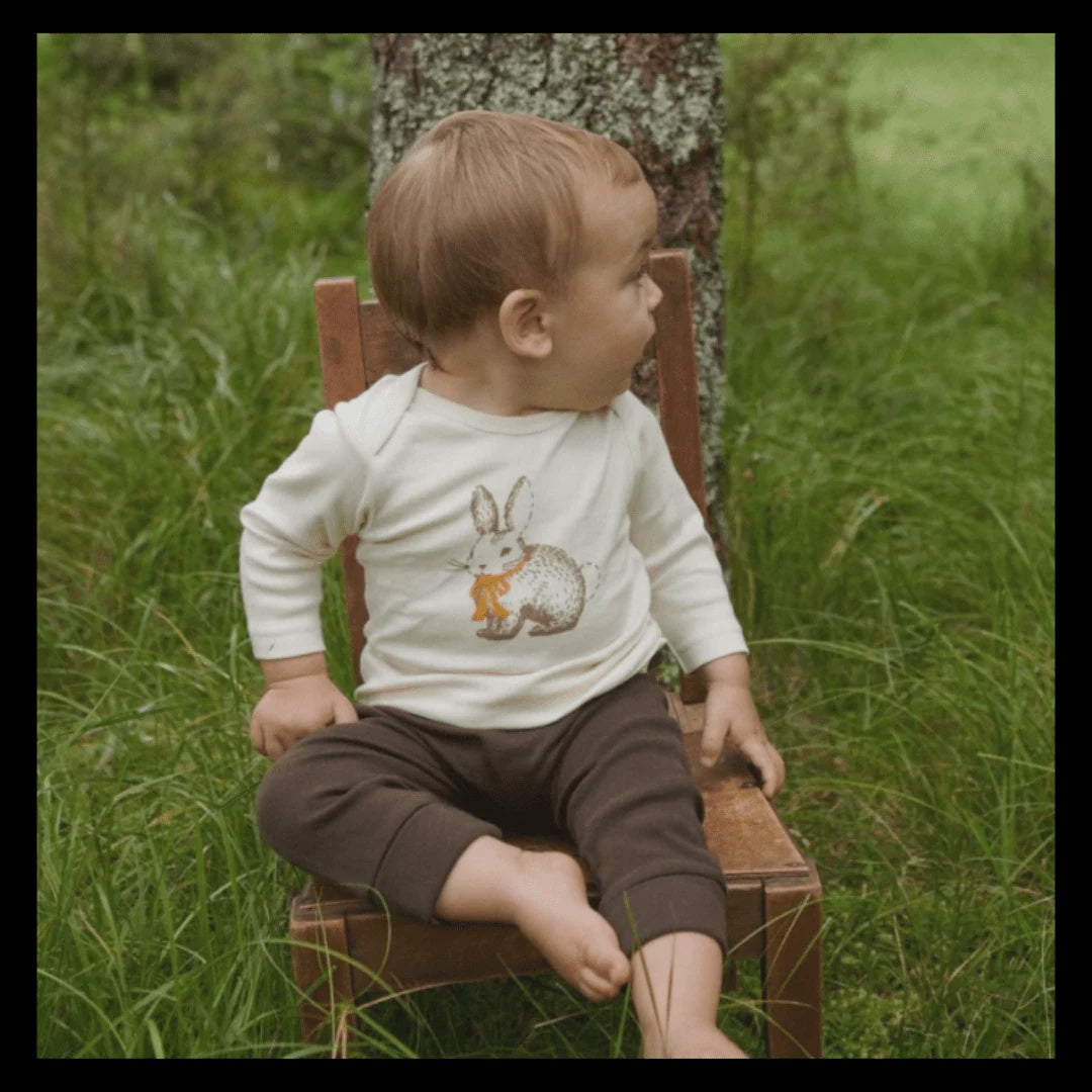 Child sitting on a wooden chair outdoors with a natural background