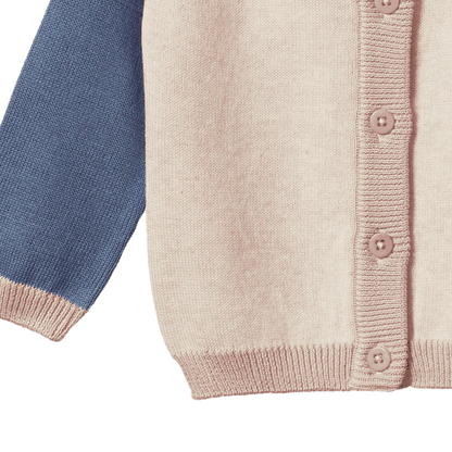 Close-up of a knitted cardigan with blue sleeve and pink buttons on a white background