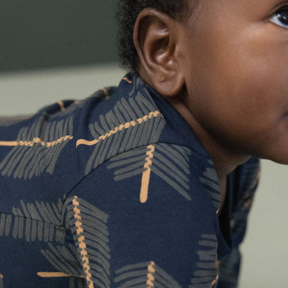 Person wearing a navy blue patterned shirt with gold accents