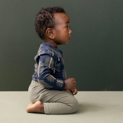 Child sitting on a plain surface with a dark green background