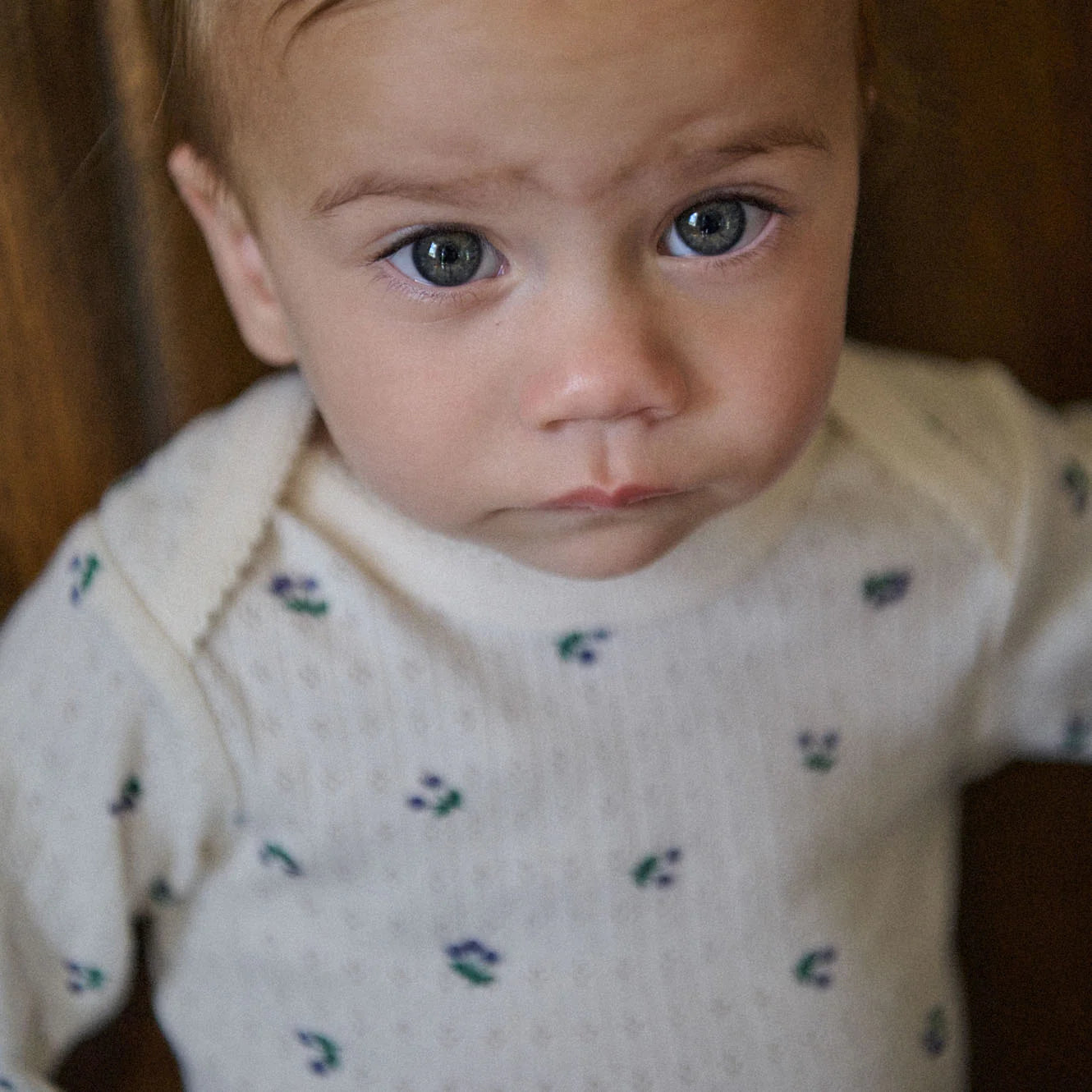 Child wearing a white sweater with small colorful patterns
