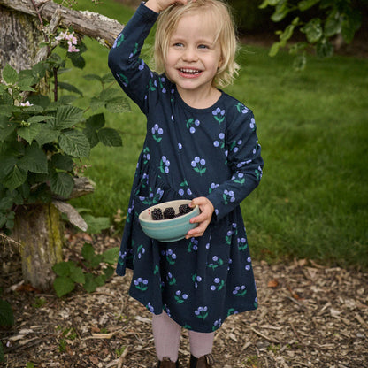Young girl in a garden holding a bowl of blackberries