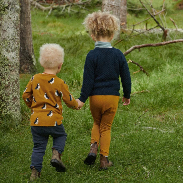 Two children holding hands in a forest setting