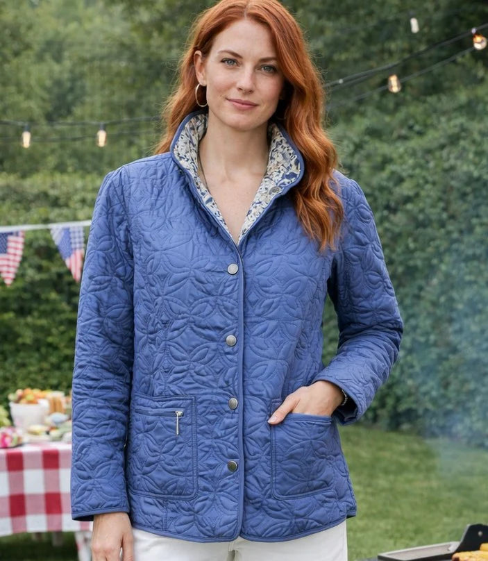 Woman wearing a blue quilted jacket outdoors with greenery in the background