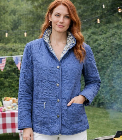 Woman wearing a blue quilted jacket outdoors with greenery in the background