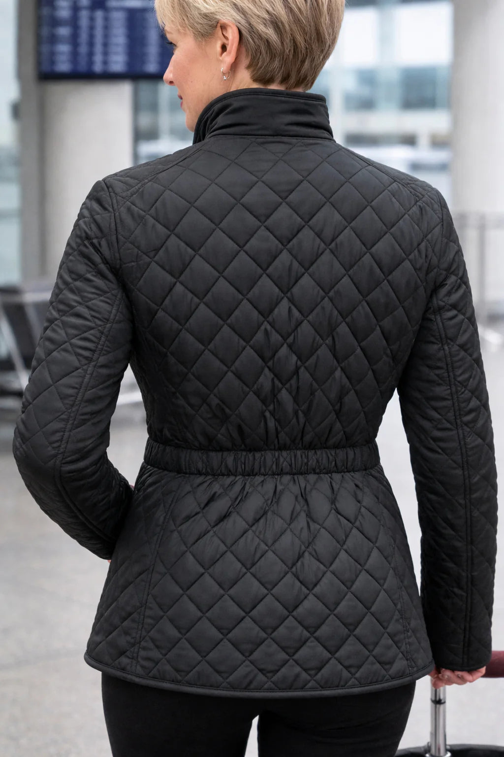 Person wearing a black quilted jacket in an indoor setting