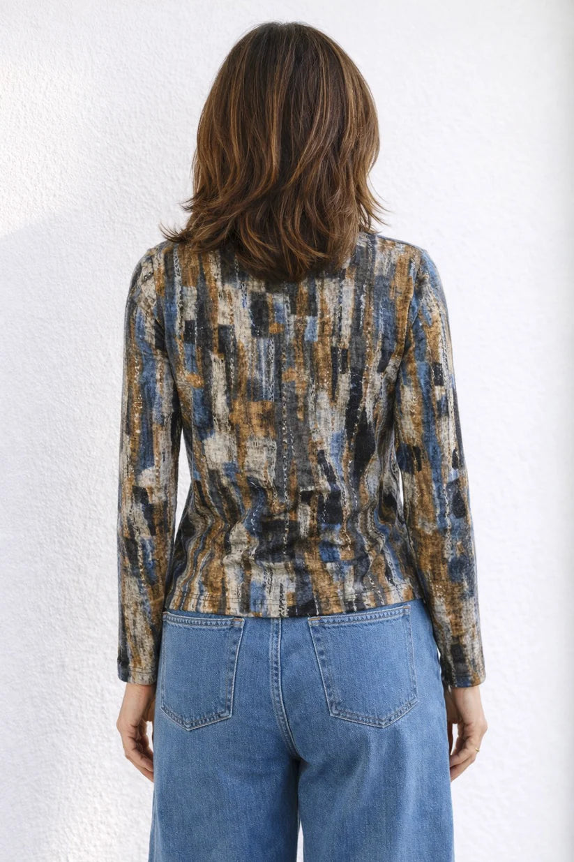 Person wearing a patterned jacket and blue jeans against a white background