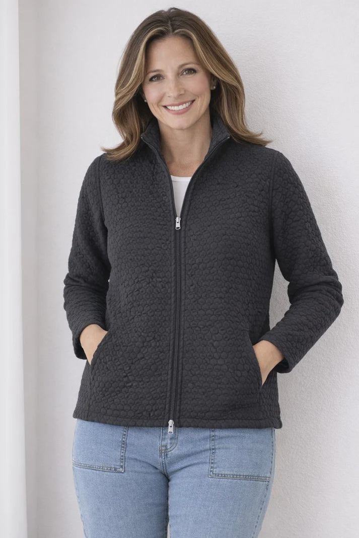 Woman wearing a dark gray zip-up jacket against a light background