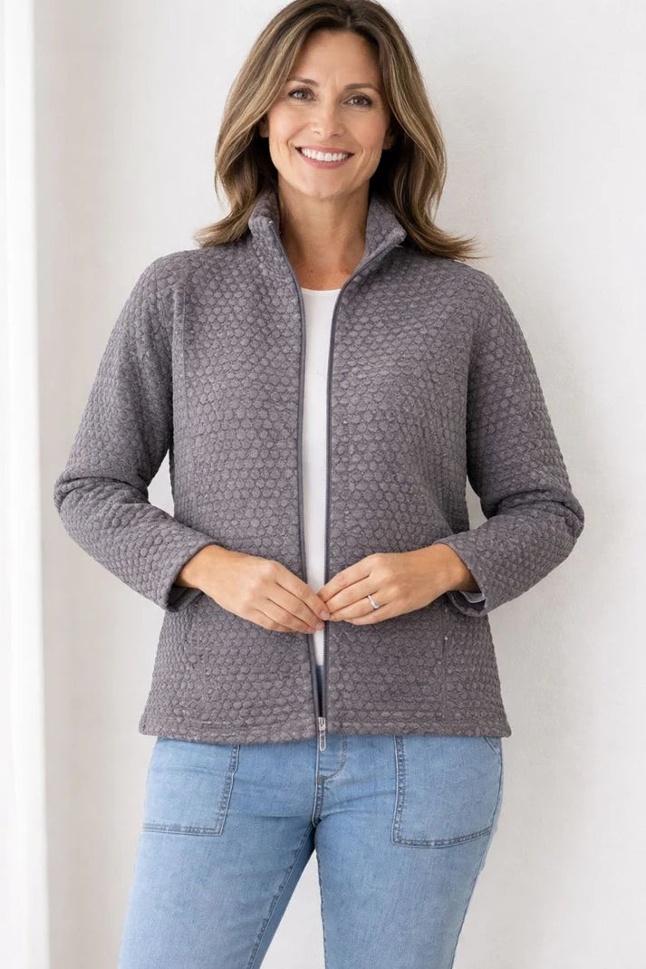 Woman wearing a gray quilted jacket and blue jeans against a white background