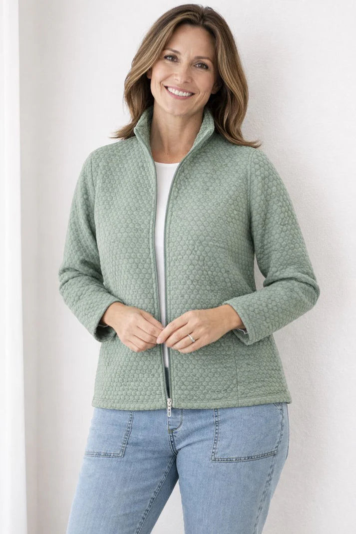 Woman wearing a green jacket and blue jeans against a white background