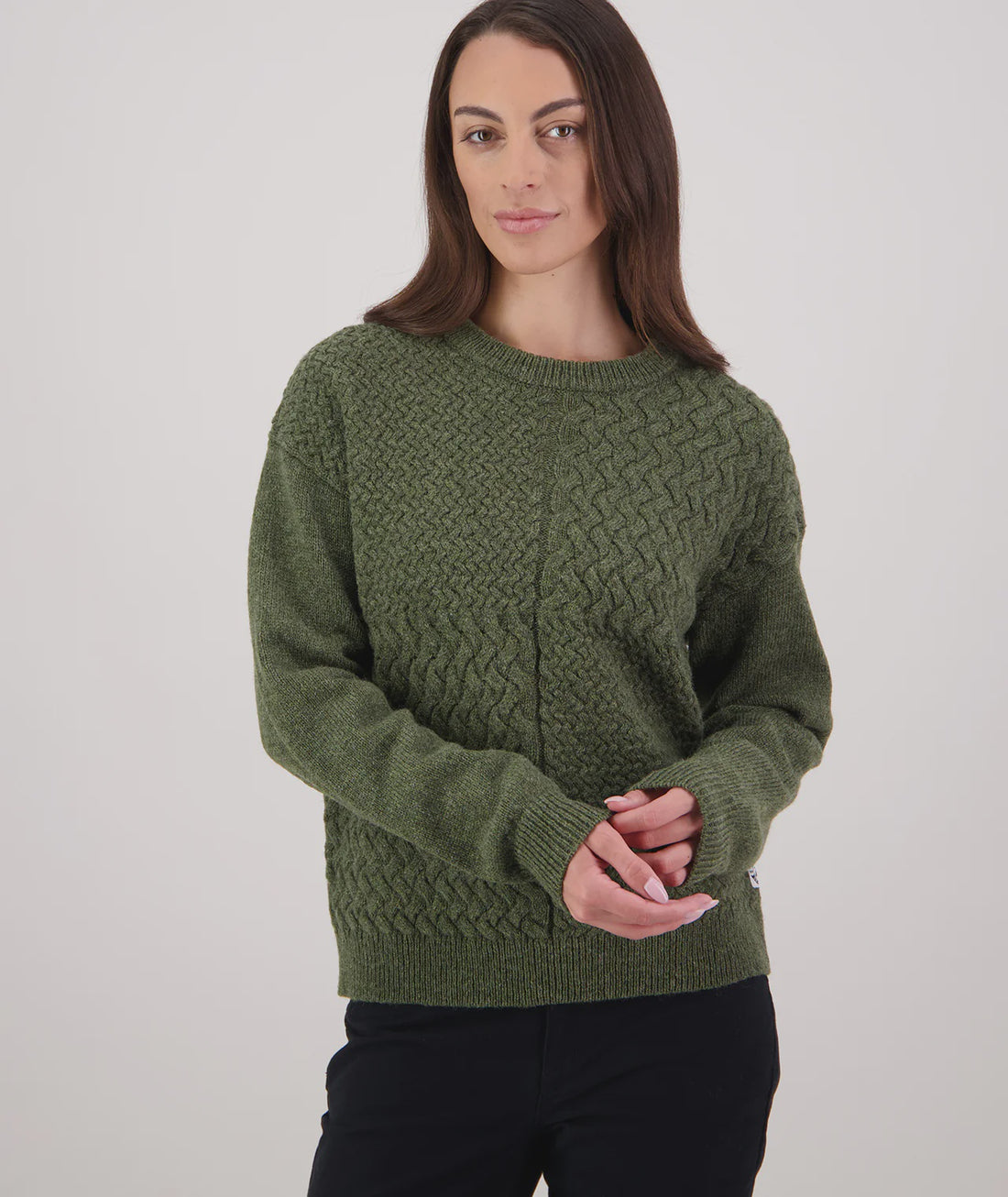 Woman wearing a green knitted sweater on a plain background