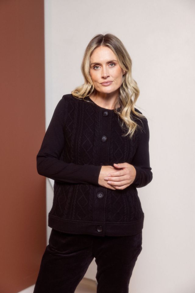 Woman wearing a black textured cardigan against a plain background