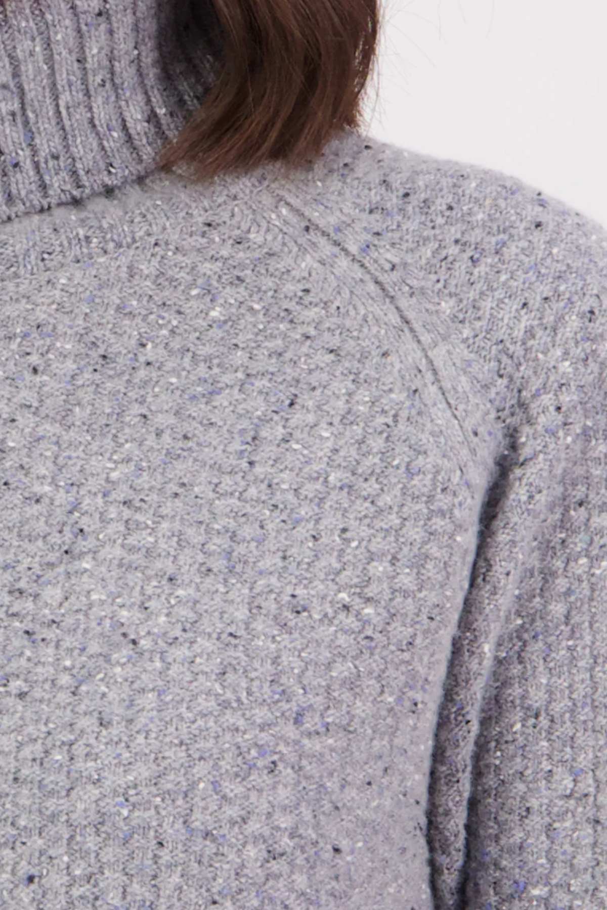 Close-up of a textured gray sweater with a person wearing it.