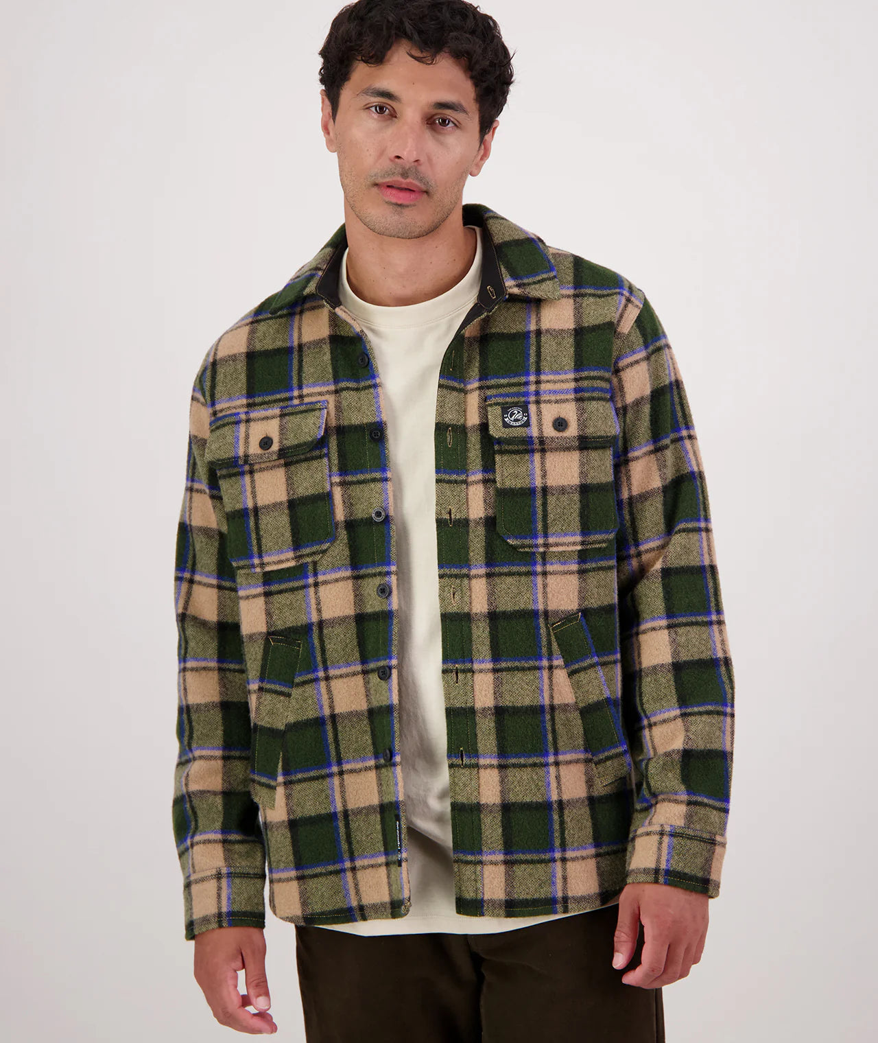 Man wearing a green and beige plaid jacket on a white background