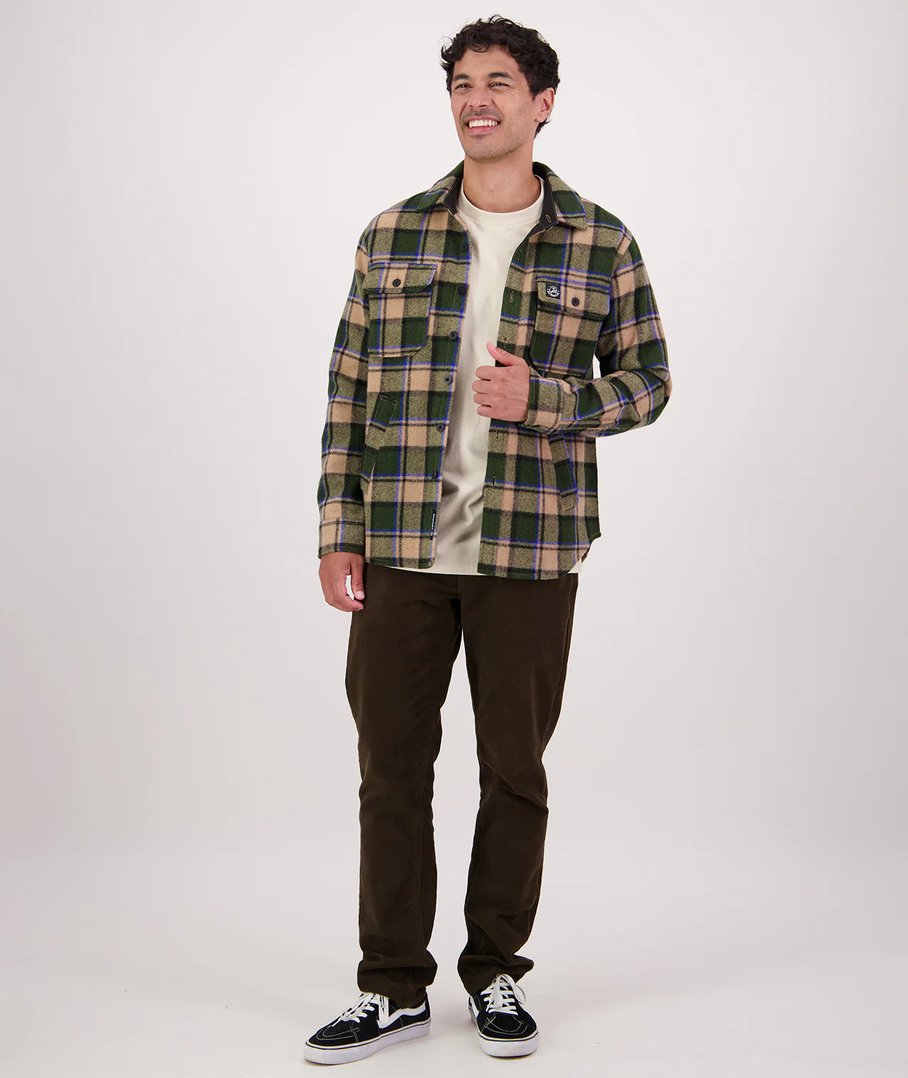 Man wearing a plaid shirt and dark pants on a white background