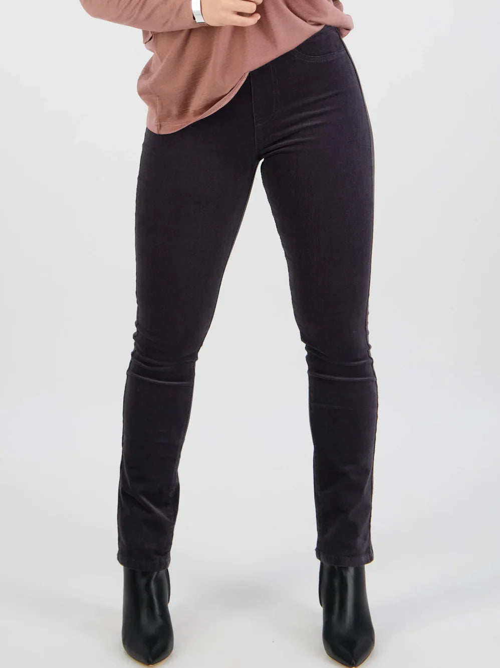 Person wearing black pants and black boots on a white background