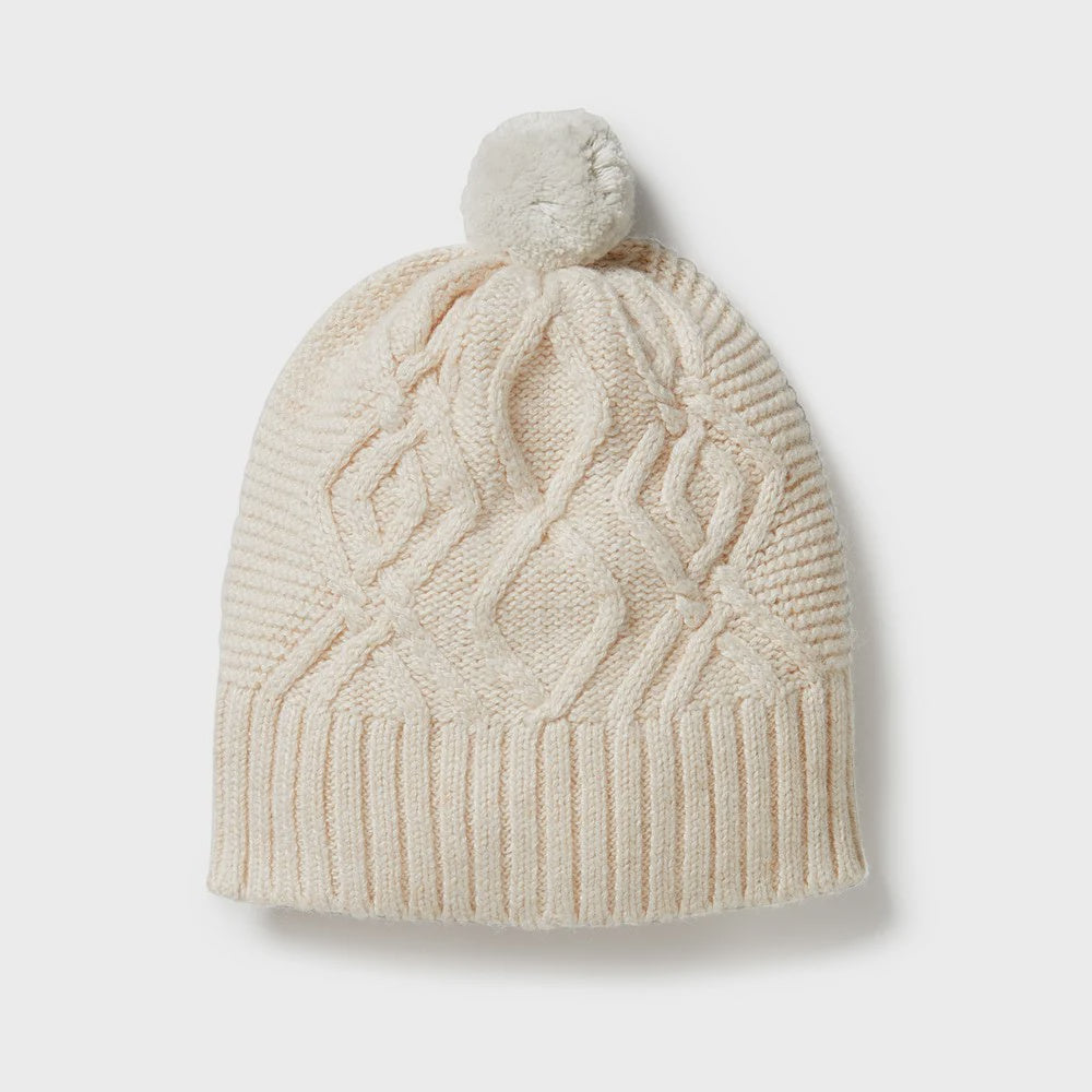 Beige knitted beanie with a pom-pom on a light gray background