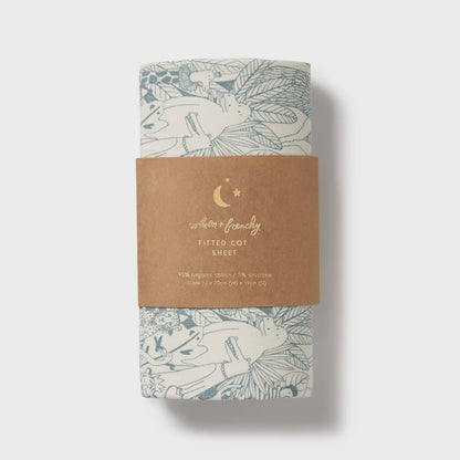 Fitted cot sheet with fox design on a cardboard packaging against a white background