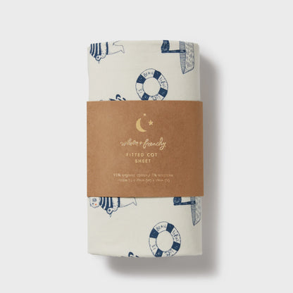Fitted cot sheet with nautical pattern and brown label on a white background