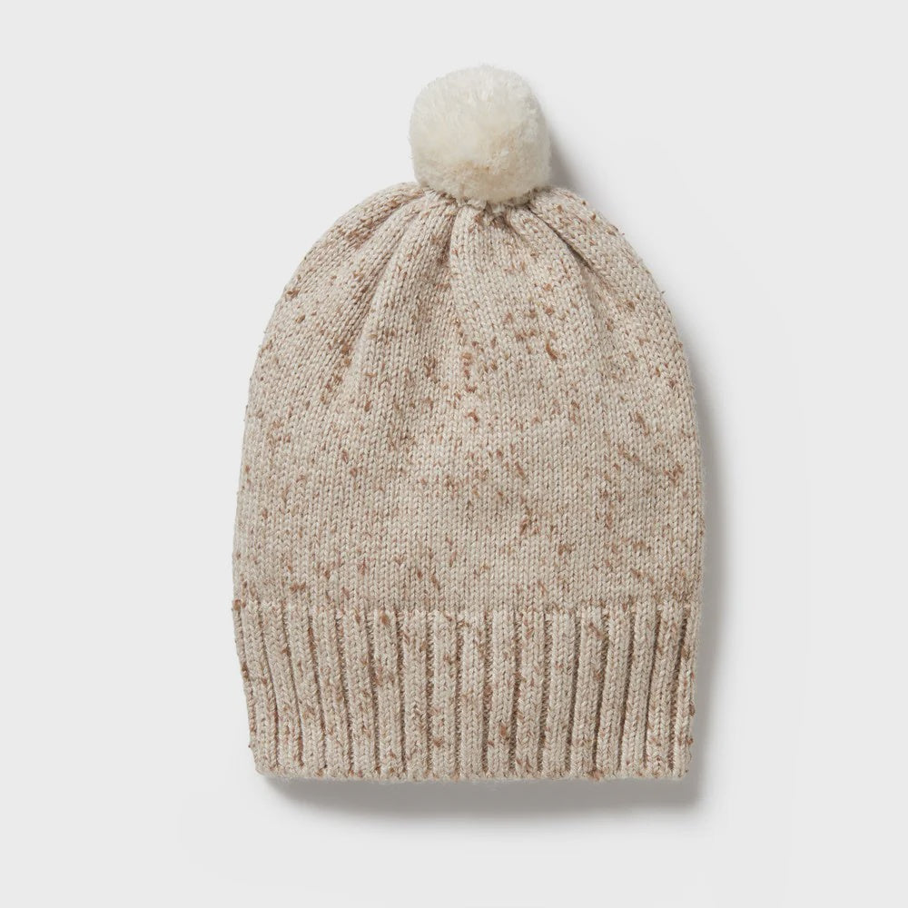 Beige knit beanie with a pom-pom on a light gray background