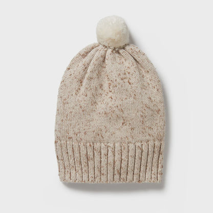 Beige knit beanie with a pom-pom on a light gray background